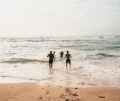 4 Personen laufen am Strand ins Wasser - Kite2Connect